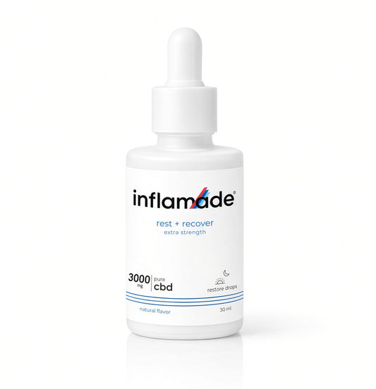 A white bottle of inflamade 'rest + recover' CBD restore sleep drops with a white dropper cap, set against a clean white background with a subtle reflection.